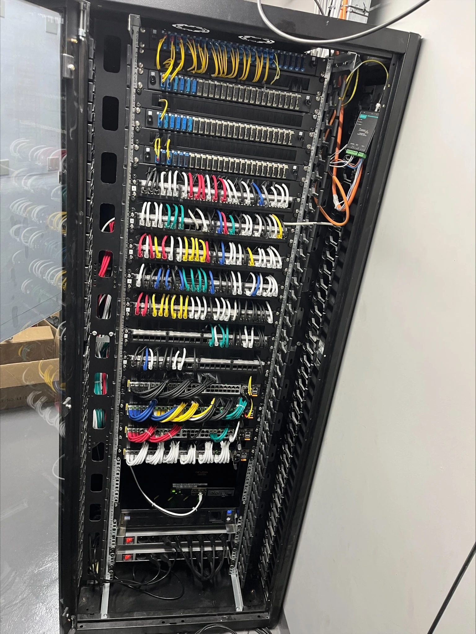 Baie réelle de brassage réseau avec liaisons fibre et cordons organisés par couleur