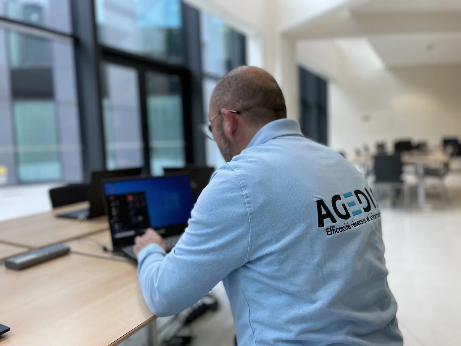 Intervenant Agedis de dos travaillant sur un ordinateur portable.